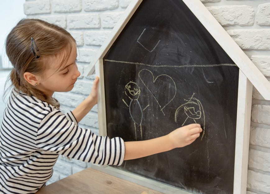 little girl draws on house shape chalkboard