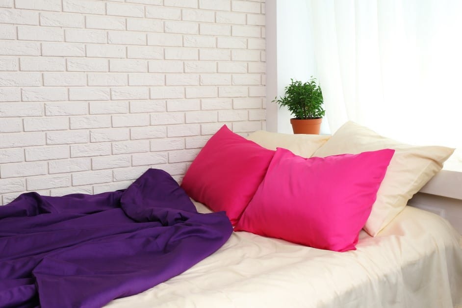 comfortable bed with pink pillows and purple blanket