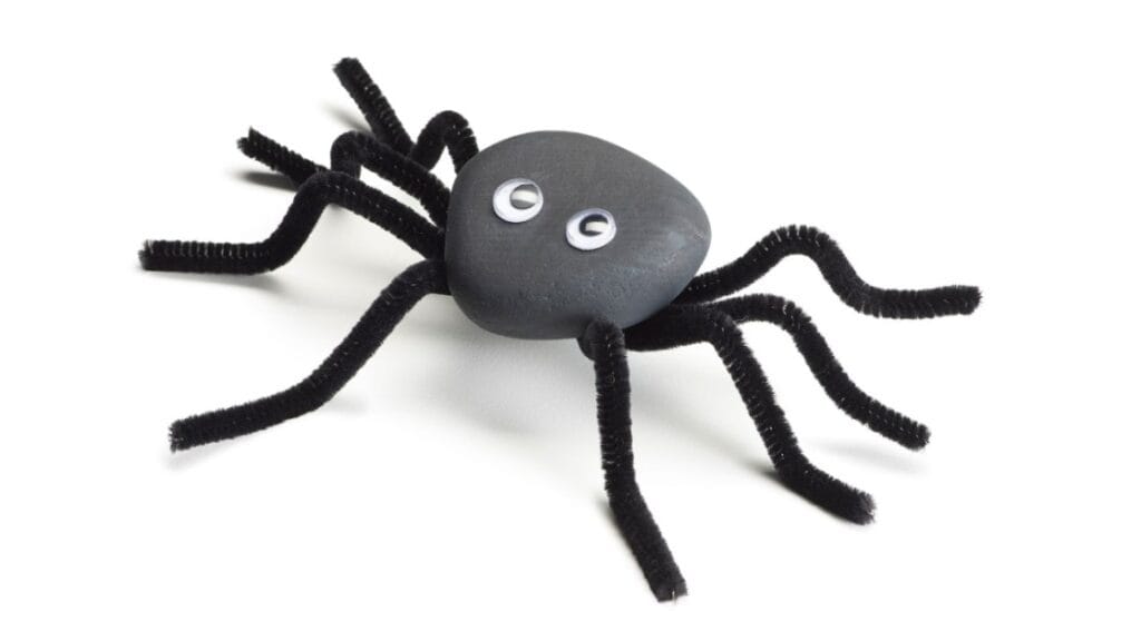 Craft spider made from black rock and pipe cleaners for Halloween craft decor.
