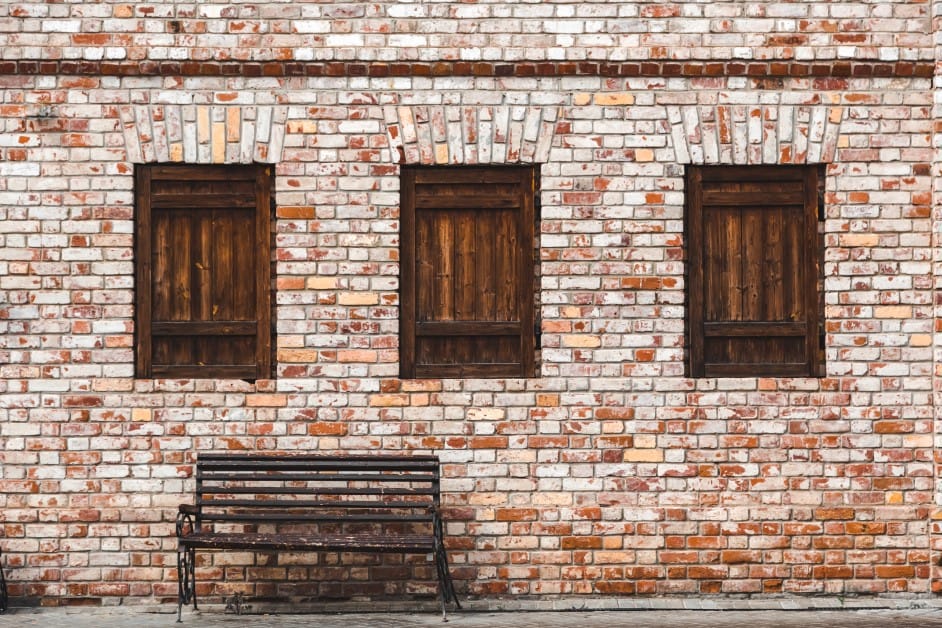 Fire resistant brick house façade with three windows and a bench