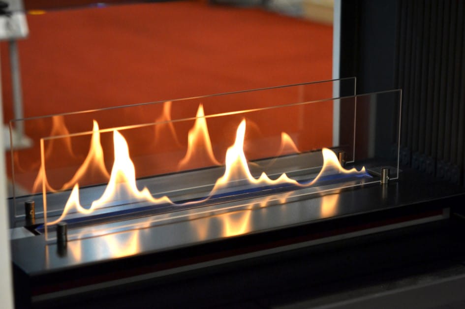Flames burning in a decorative bioethanol fireplace, shielded by a fire-grade glass barrier.