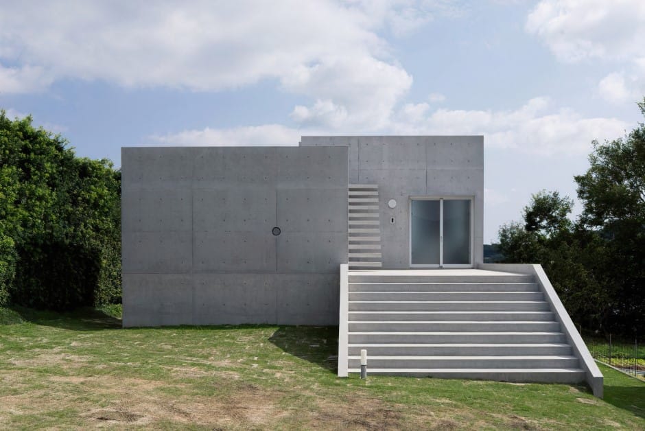 Exterior view of a box-like, fire-resistant building, constructed of monolithic concrete panels, set in a grassy yard