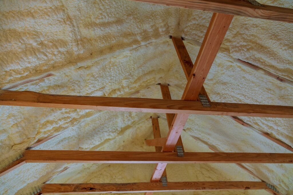 Foam insulation applied under a roof with exposed wooden beams