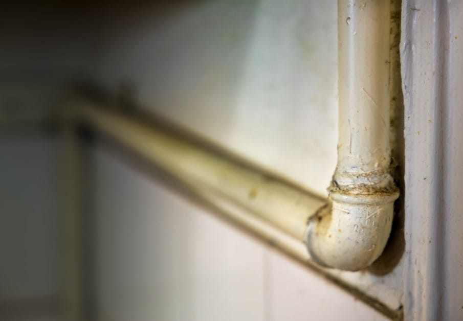 metal gas pipe in a kitchen corner, showing slight corrosion and grime buildup