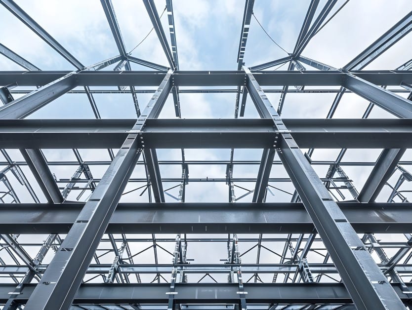 Low-angle view of a large, gray steel framework structure against a cloudy sky