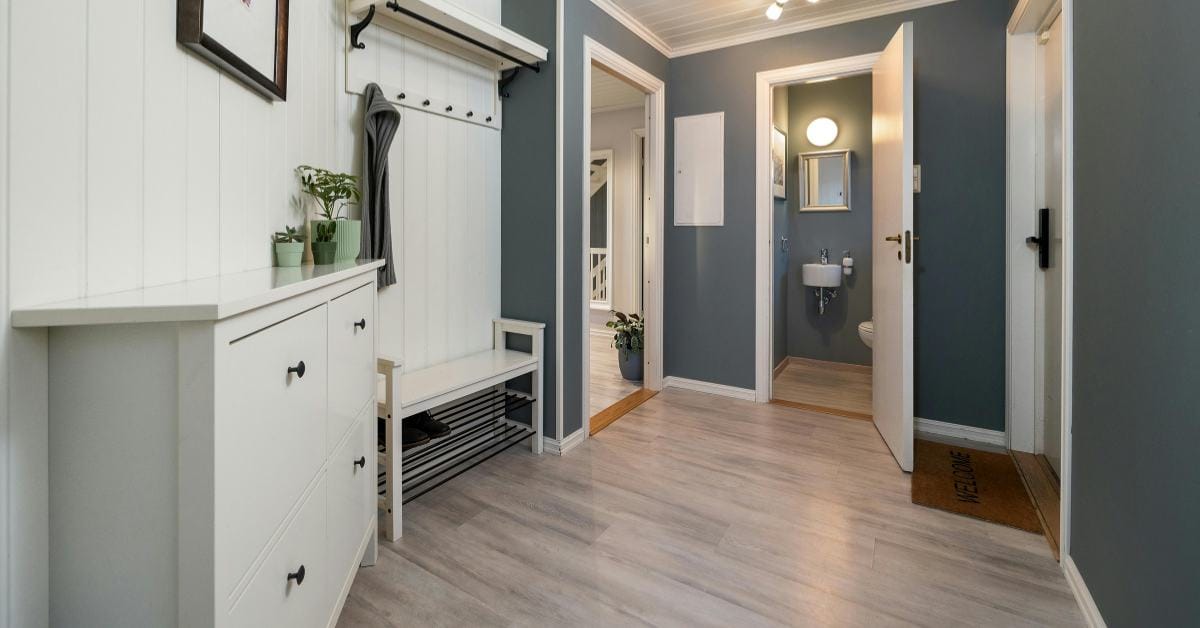 Compact entryway uses white furniture and light flooring against dark walls to expand the narrow space.