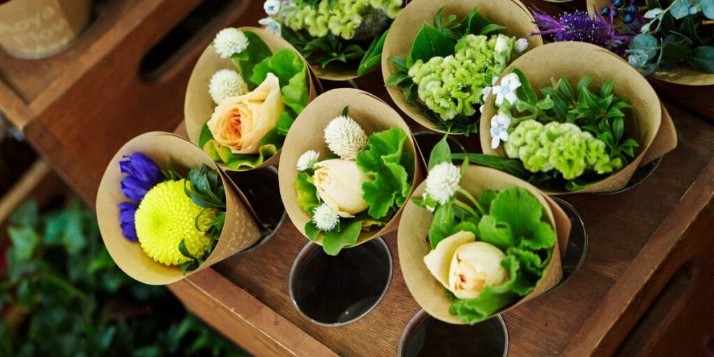 Multiple small floral Valentine's flower bouquets wrapped in brown paper, organized in a wooden display crate.