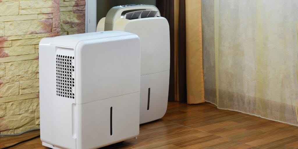 Two high-capacity white dehumidifiers running to prevent mold spores from spreading