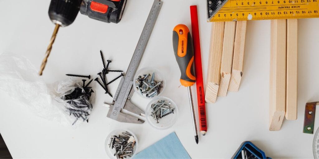 DIY woodworking project layout with power drill, screws, calipers, and wood lumber.