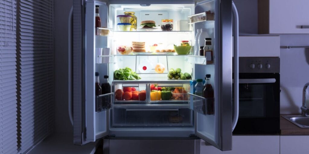 An open kitchen refrigerator full of food, a major hotspot for hidden bacteria and spills.