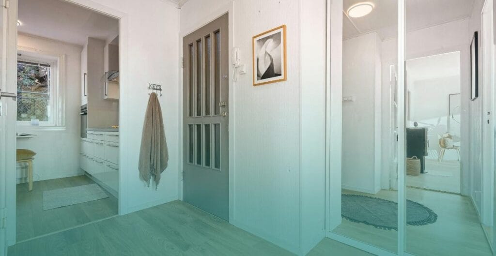 A large mirror hangs in a small rental apartment entryway, reflecting the space to make it feel brighter and larger.